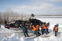 При помощи тросов и спасателей вертолет волоком затаскивают для погрузки